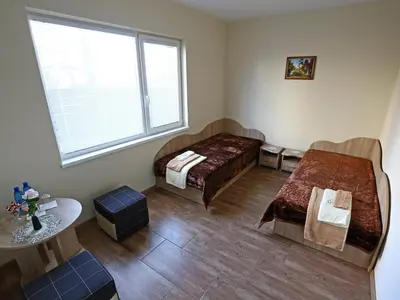 a room with two beds and a table and a window at Juro Guest House in Šiauliai
