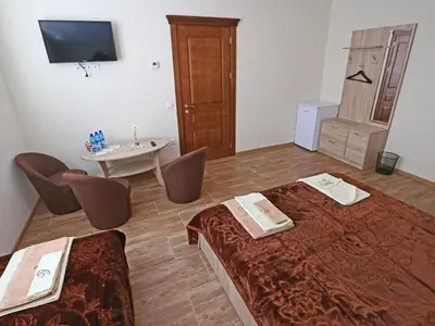 a room with two beds and a table and a television at Juro Guest House in Šiauliai