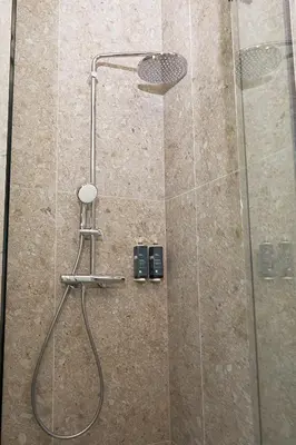 a shower with a glass door with a stool in it at Air Hotel in Karmėlava
