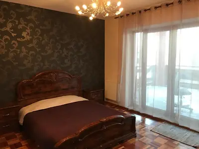 a bedroom with a bed and a window with a chandelier at Villa Midesta in Šiauliai