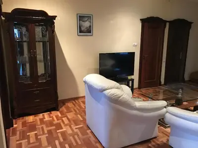 a living room with a white chair and a television at Villa Midesta in Šiauliai