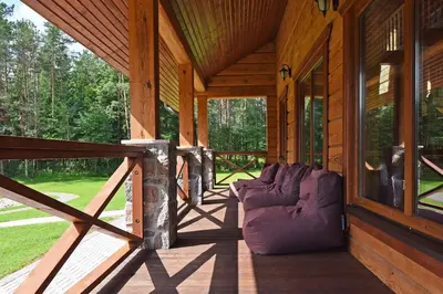 a porch of a wooden cabin with a purple couch at Auksinis Ąžuolas in Avižieniai