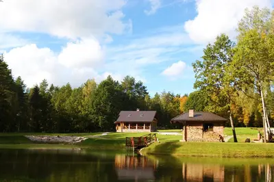 a house on a golf course with a lake in front at Auksinis Ąžuolas in Avižieniai