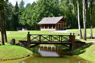 a bridge over a pond in front of a cabin at Auksinis Ąžuolas in Avižieniai