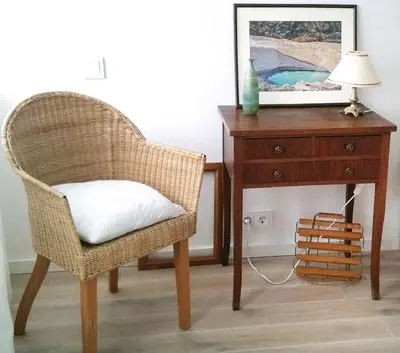 a wicker chair sitting next to a table with a lamp at Nijole ir Algimantas in Anykščiai