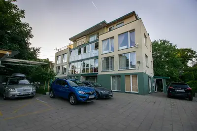 a building with three cars parked in a parking lot at Jaukūs apartamentai Free parking in Vilnius