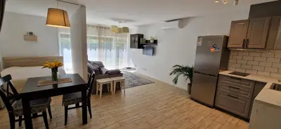 a kitchen and living room with a table and a refrigerator at Jaukūs apartamentai Free parking in Vilnius
