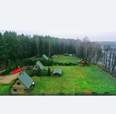 a group of houses on a green field with trees at Pas Kaziuką namukas in Palūšė