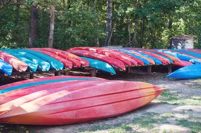 a group of kayaks lined up in a row at Pas Kaziuką namukas in Palūšė