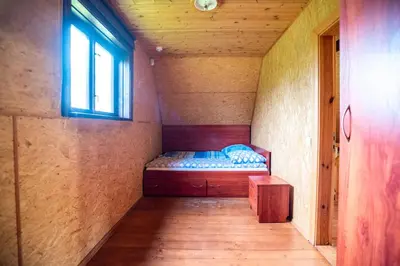 a small bed in a small room with a window at Pas Kaziuką namukas in Palūšė