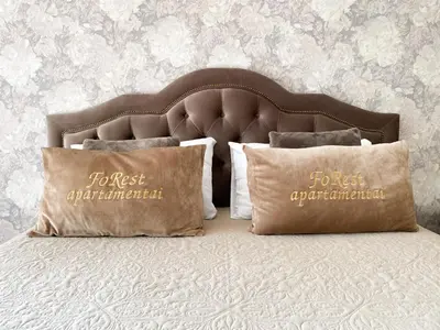 a bed with two pillows on top of it at FoRest Apartments in Druskininkai