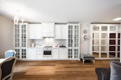 a kitchen with white cabinets and wooden floors at FoRest Apartments in Druskininkai