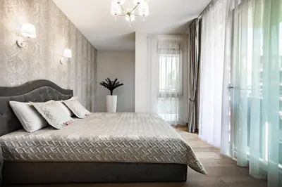 a bedroom with a large bed and a chandelier at FoRest Apartments in Druskininkai
