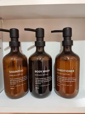 three bottles of shampoo and conditioner on a shelf at Airida Forest Apartment in Druskininkai