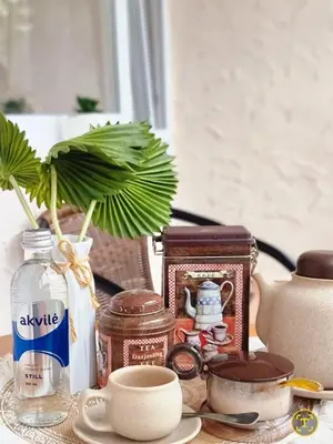 a table with a vase with a plant and other items at Airida Forest Apartment in Druskininkai