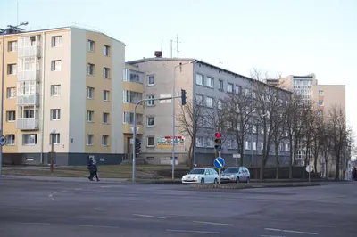a person crossing a street at an intersection with buildings at Siauliai Apartments - Ežero in Šiauliai
