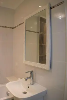 a white bathroom with a sink and a mirror at Siauliai Apartments - Ežero in Šiauliai