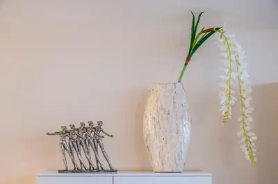 a white vase sitting on a table with a plant in it at Hills Park Luxury Apartment in Vilnius