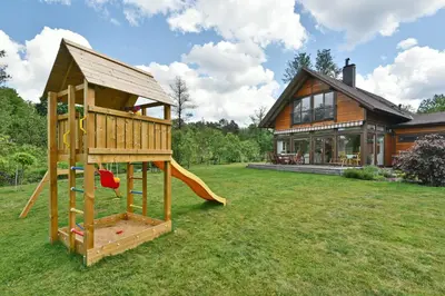 a wooden play house with a slide in front of a house at Atostogų namelis Druskininkuose in Druskininkai