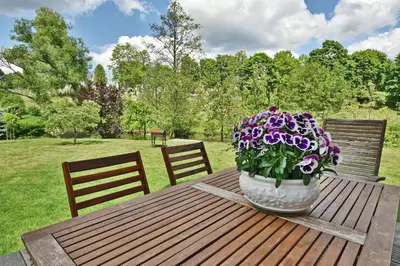 a vase of purple flowers sitting on a wooden table at Atostogų namelis Druskininkuose in Druskininkai