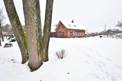 a house in the snow with trees in front at Atostogų namelis Druskininkuose in Druskininkai