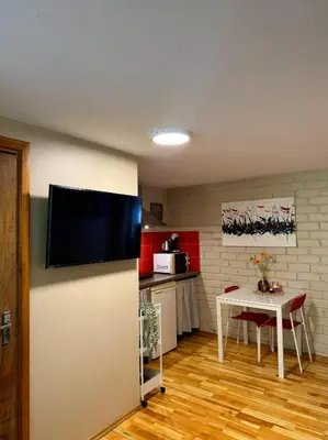 a kitchen with a table and a television on a wall at Little house in Kaunas