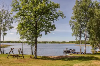 a park with a swing and a dock on a lake at Duriu sodyba in Molėtai