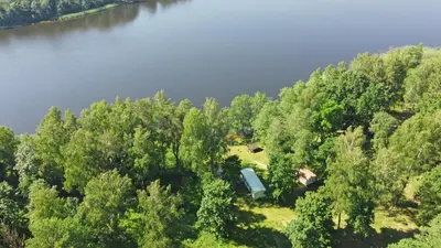 an aerial view of a lake with a house in the trees at Duriu sodyba in Molėtai