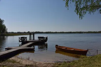 a dock with a boat and a table and a bench at Duriu sodyba in Molėtai