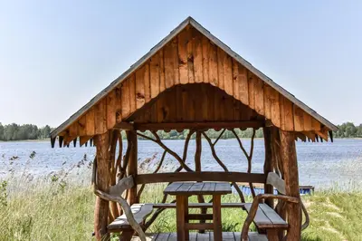 a wooden gazebo with two chairs and a table at Duriu sodyba in Molėtai