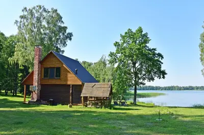 a log cabin on the shore of a lake at Duriu sodyba in Molėtai