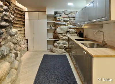 a kitchen with a stone wall and a sink at Six Apartment Simona in Vilnius