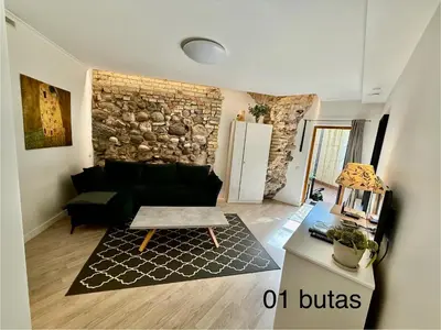 a living room with a couch and a stone wall at Six Apartment Simona in Vilnius
