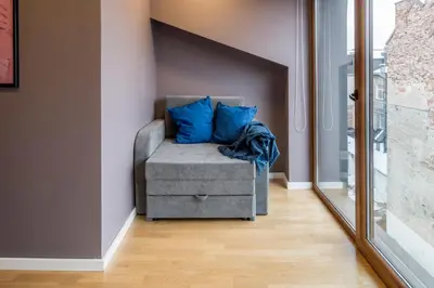 a gray chair with blue pillows in a room at Maironis apartment 2 in Kaunas