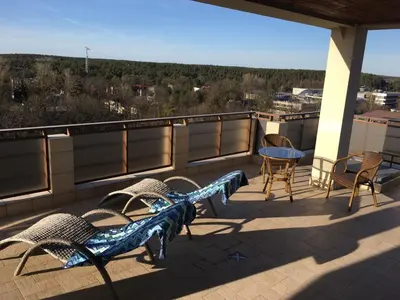 a patio with chairs and a table on a roof at Panorama Apartment in Druskininkai