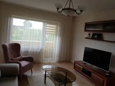 a living room with a television and a chair and a table at Apartamentai Gertrūda in Druskininkai