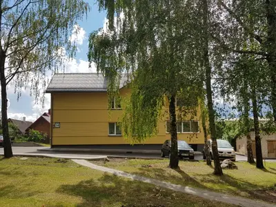 a yellow house with a car parked in front of it at Apartamentai Gertrūda in Druskininkai