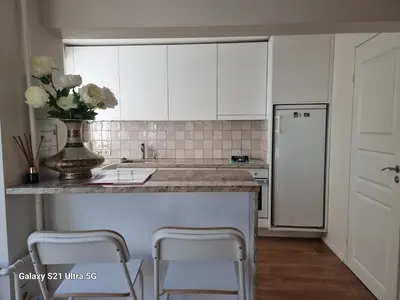 a kitchen with white cabinets and a vase of flowers at Stilingi apartamentai su virtuve Trakų miesto centre in Trakai