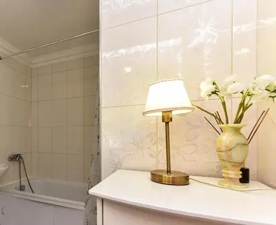 a table with a lamp and a vase with flowers at Stilingi apartamentai su virtuve Trakų miesto centre in Trakai