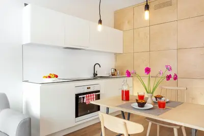 a kitchen with a dining table and a kitchen with white cabinets at #stayhere - Modern Designer 1BDR Apartment in Artistic District in Vilnius