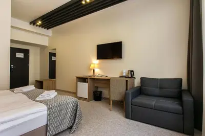 a hotel room with a bed and a chair and a desk at Old Town Trio in Vilnius