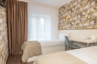 a hotel room with two beds and a desk and a window at Kesminta Apartments in Vilnius