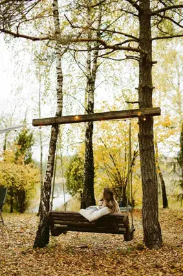 a woman sitting on a swing in a park at Beržų namelis - Birch cabin in Kučiūnai