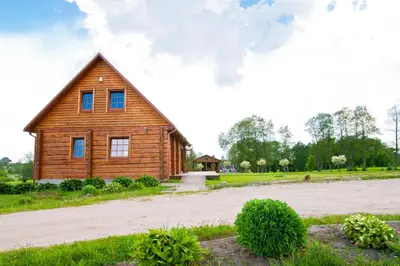 a wooden house with a driveway in front of it at Adomo Sodyba in Dubingiai
