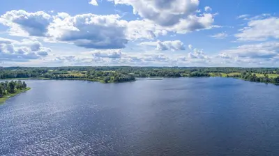 an aerial view of a lake with trees and clouds at Adomo Sodyba in Dubingiai