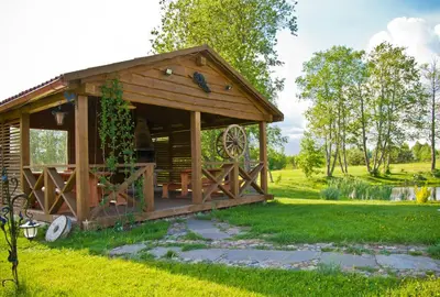 a wooden cabin in a grassy field at Adomo Sodyba in Dubingiai