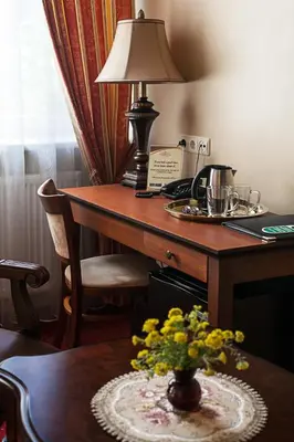 a desk with a lamp and a vase of flowers on a table at Conviva in Panevėžys