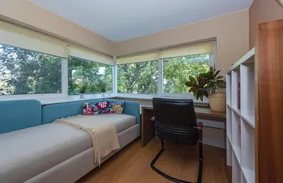 a bedroom with a bed and a chair and windows at Domido Villa in Trakai