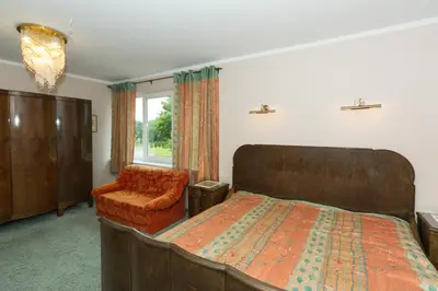 a bedroom with a bed and a chair and a window at Kernavės centras in Kernavė
