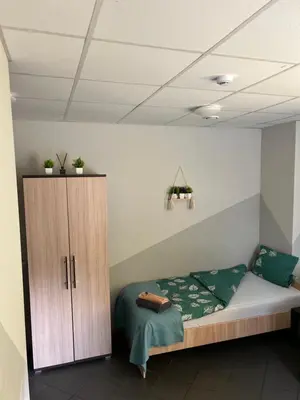 a bedroom with a bed and a wooden cabinet at Šiauliu apartamentai in Šiauliai